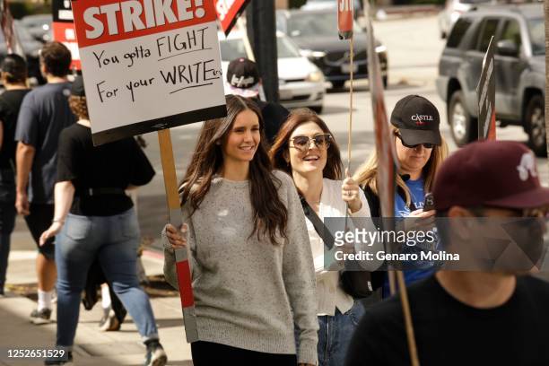 Actor and screenwriter Nina Dobrev, left, and Sarah Adina, sunglasses, join fellow WGA members who walk the picket line across the street from Warner...