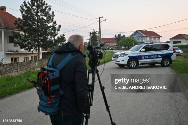 Man uses a camera to film police vehicles blocking a road in the village of Dubona near the town of Mladenovac, about 60 kilometres south of Serbia's...