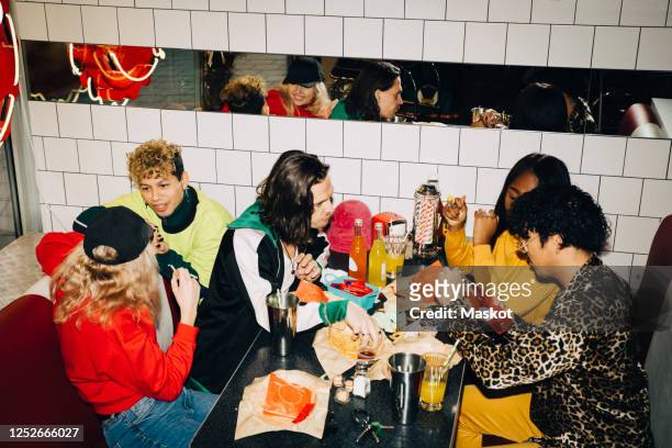 high angle view of male and female friends talking at table in cafe - black man high 5 stockfoto's en -beelden