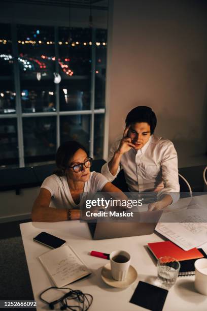 high angle view of female and male entrepreneurs sitting at desk during late night meeting in office - business talk sit men stock-fotos und bilder