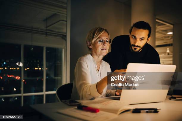 businessman listening to mature businesswoman during meeting at late night in office - business talk petite phrase photos et images de collection