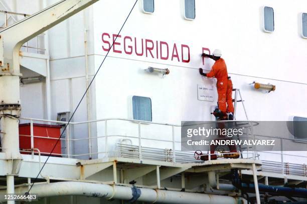 Worker paints a sign on an oil tanker in Maracaibo, Venezuela 09 December 2002. Un marinero del buque petrolero Moruy, pinta un letrero de seguridad...