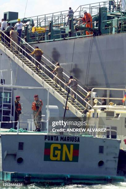 Military officials are seen on the hull of an oil tanker in the seas of Maracaibo, Venezuela where demonstrators have surrounded the vessel in...