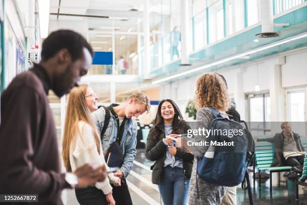 cheerful young male and female students talking while standing in cafeteria at university - campus ストックフォトと画像