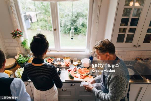 high angle view of senior man and woman preparing dinner at kitchen counter - schürze mann rückansicht stock-fotos und bilder