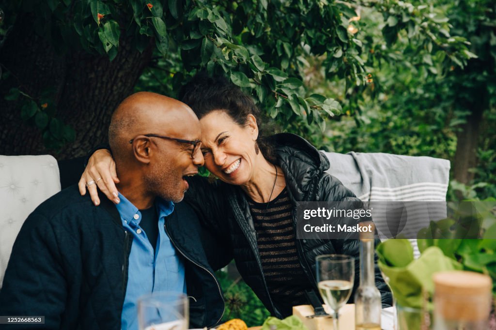 Cheerful senior man and woman enjoying while sitting at dinning table during garden party