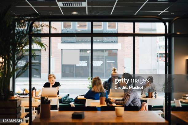 multi-ethnic customers sitting in coffee shop - coffee shop stock pictures, royalty-free photos & images