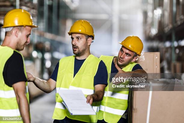 frustrated manual workers arguing with their colleague in a warehouse. - frustrated workman stock pictures, royalty-free photos & images