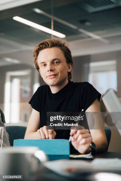 businesswoman discussing with transgender colleague over laptop in board room during meeting - androgynous stock-fotos und bilder