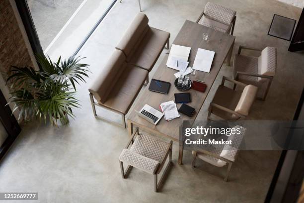 high angle view of documents and laptop on desk amidst chairs at law firm - law firm stock pictures, royalty-free photos & images