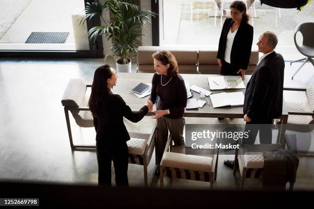 smiling senior businesswoman greeting female lawyer with handshake during meeting at office - lawyer handshake stock pictures, royalty-free photos & images