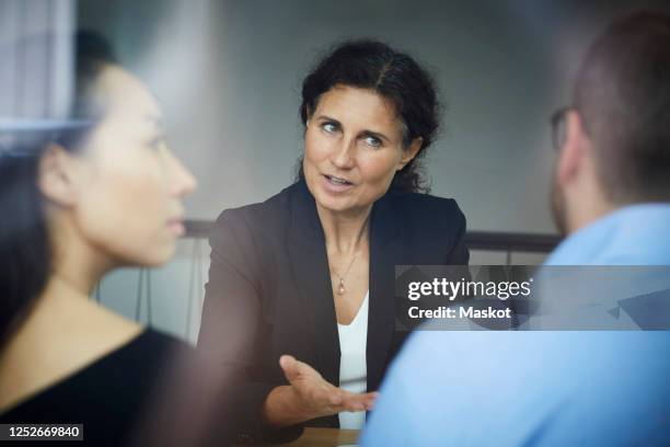 confident mature female financial advisor discussing with businessman and businesswoman during meeting at office - financial advice stock-fotos und bilder