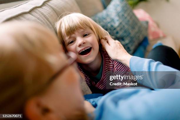 cheerful boy with grandmother on sofa at home - grandmother granddaughter stock pictures, royalty-free photos & images