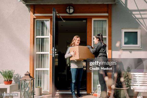 female customer receiving box from young delivery woman - 宅配便サービス ストックフォトと画像