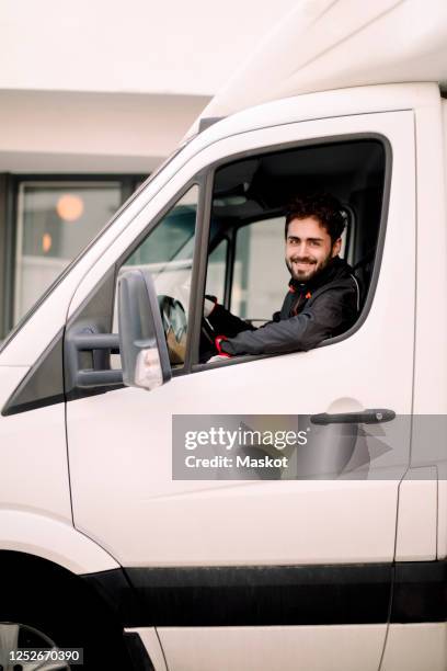 portrait of smiling young delivery man driving truck - véhicule utilitaire et commercial photos et images de collection