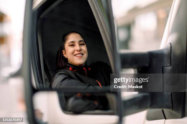 portrait of smiling young delivery woman driving truck - truck driver stock pictures, royalty-free photos & images