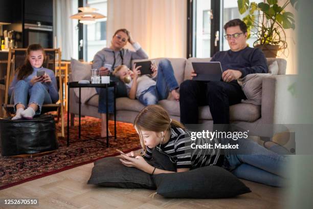 family is using technologies in living room at modern home - gear stockfoto's en -beelden