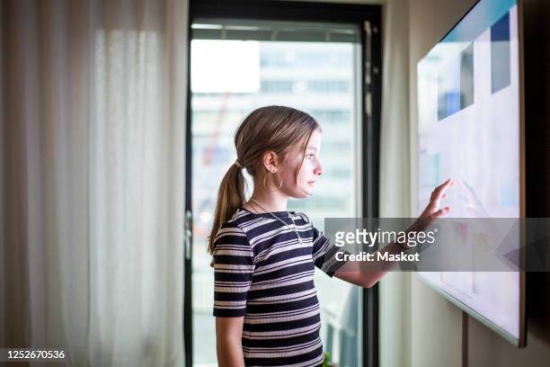girl touching digital screen of smart tv at modern home - girls modern room stock-fotos und bilder