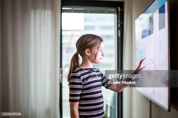 girl touching digital screen of smart tv at modern home - smart tv living room stock pictures, royalty-free photos & images