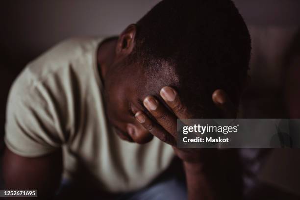 close-up of man holding head in hand worriedly - great depression stock-fotos und bilder