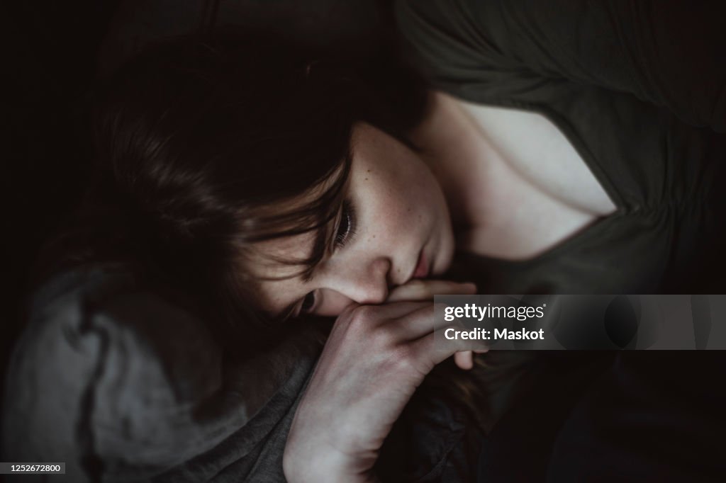 Close-up of sad woman lying on bed