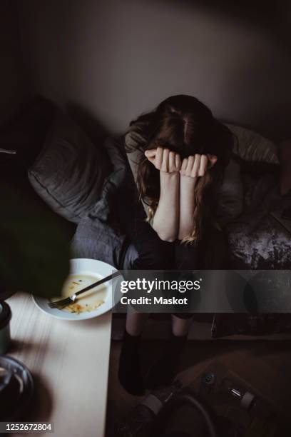 high angle view of sad woman sitting on bed - eating disorder stock-fotos und bilder