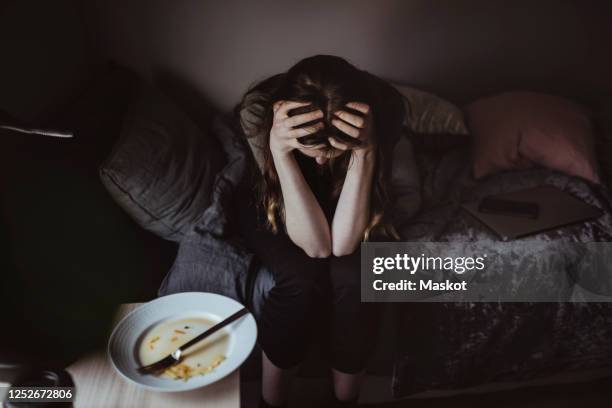 high angle view of worried woman sitting on bed - eating disorder stock pictures, royalty-free photos & images