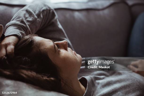 close-up of sad woman lying on sofa at home - worried fotografías e imágenes de stock