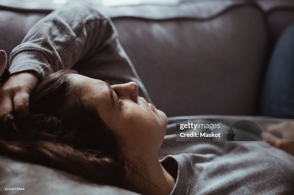 Close-up of sad woman lying on sofa at home