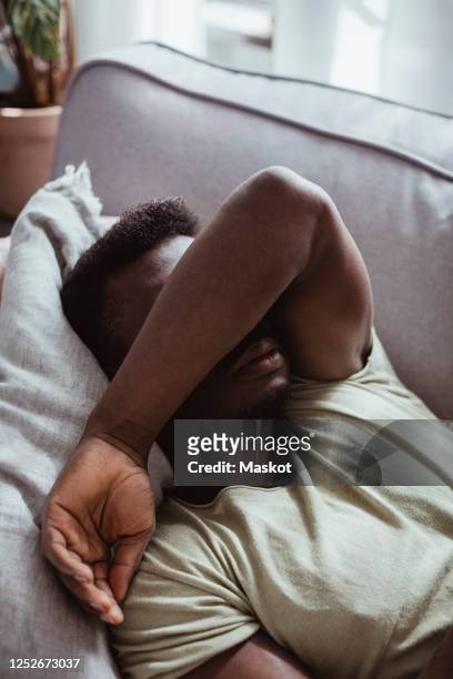 close-up of man lying on sofa in living room - mad stock pictures, royalty-free photos & images
