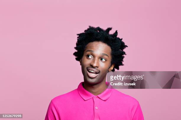 kopfschuss von überraschten jungen mann trägt rosa polo-shirt - raised eyebrows stock-fotos und bilder