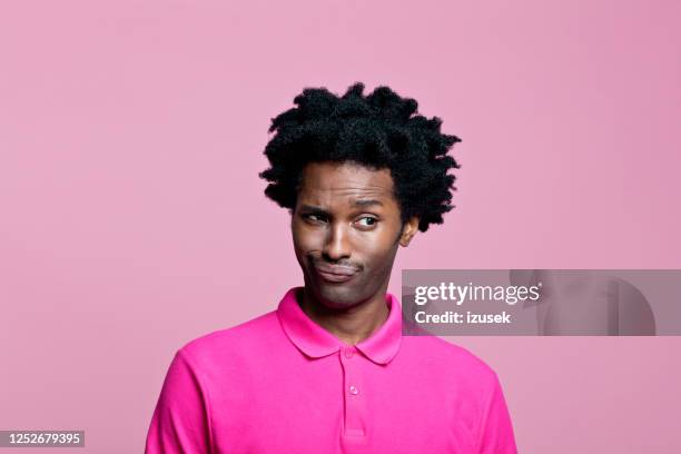 disparo en la cabeza de un joven sorprendido que lleva polo rosa - levantar las cejas fotografías e imágenes de stock