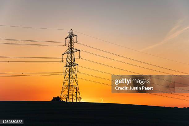 electricity pylons in the countryside at sunset - electricity pylon stock pictures, royalty-free photos & images