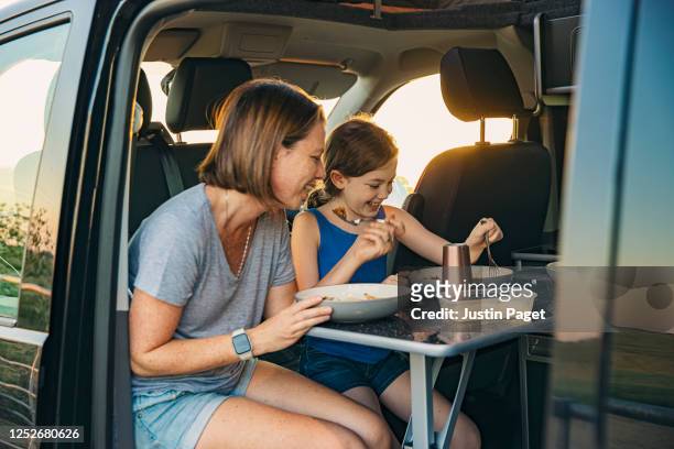 young girl and her mother eating dinner in their camper van - parent and child meal stock pictures, royalty-free photos & images