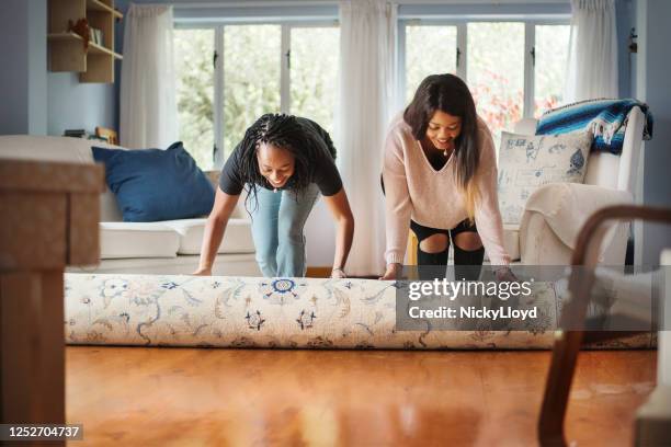 unrolling carpet in new house - gay couple new house stock pictures, royalty-free photos & images