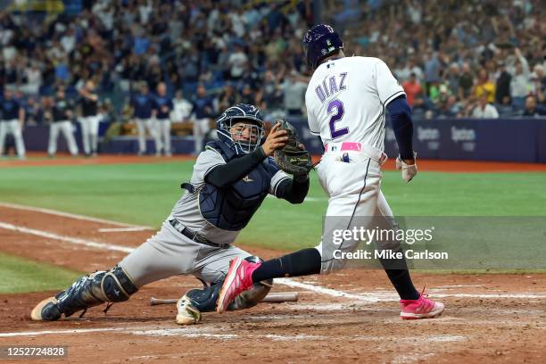 Yandy Diaz of the Tampa Bay Rays scores past Jose Trevino of the New York Yankees during the seventh inning of a baseball game at Tropicana Field on...