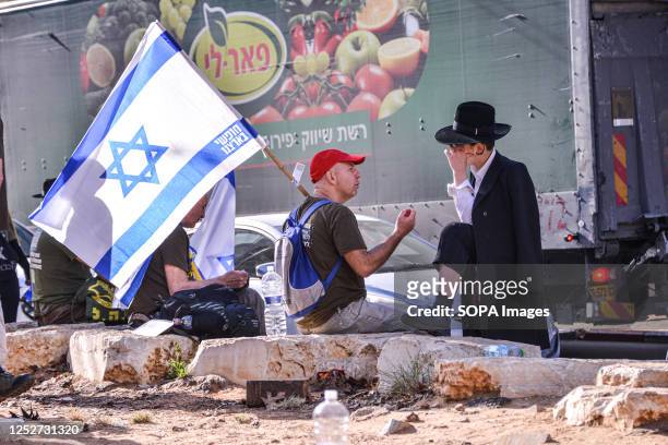 Israeli reservist against the reform holding an Israeli flag speaks with an orthodox young man during a protest against Haredi orthodox IDF exemption.