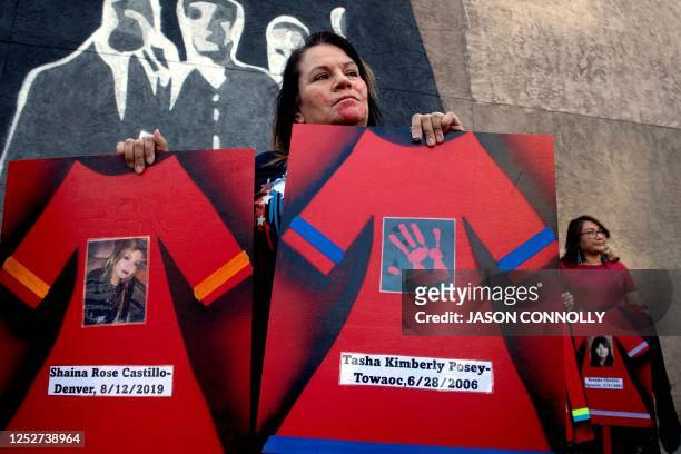 Woman holds signs depicting a red dresses during a rally supporting Missing or Murdered Indigenous Persons Awareness Day in Colorado Springs,...