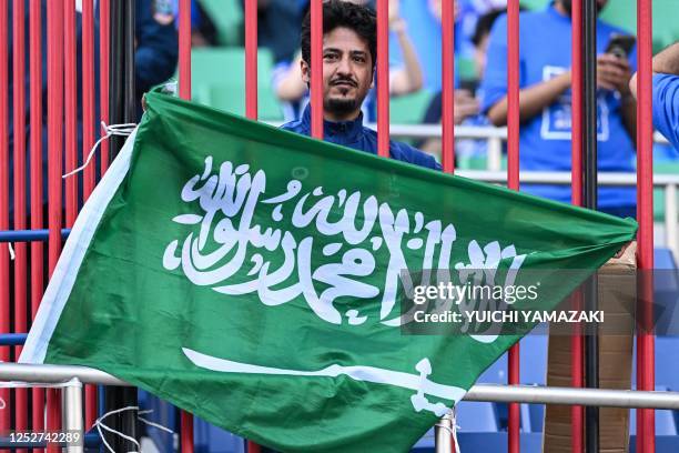 Hilal fan poses with the flag of Saudi Arabia in the stands during the second leg of the AFC Champions League final between Urawa Red Diamonds and...