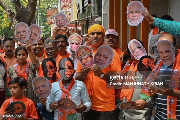 Bharatiya Janata Party workers and supporters with masks of Indian Prime Minister Narendra Modi gather as they wait to see Modi during a road rally...