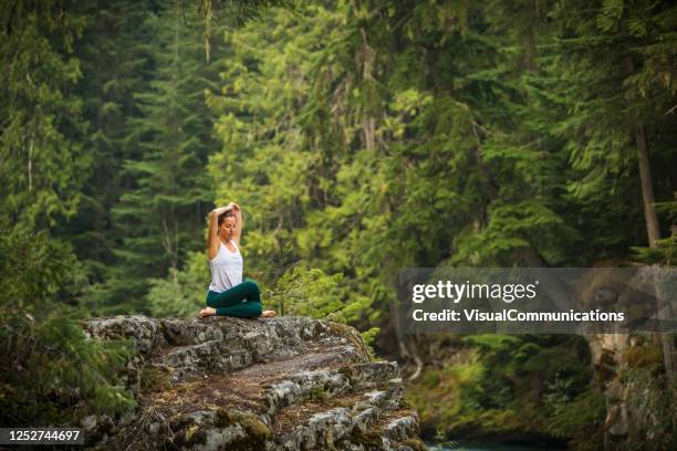 mujer joven practicando yoga y meditación en el entorno forestal. - hero pose yoga fotografías e imágenes de stock
