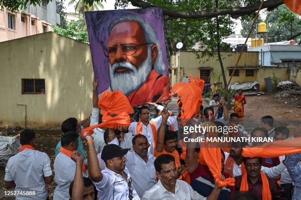 Bharatiya Janata Party workers and activists carry a portrait of Indian Prime Minister Narendra Modi as they wait to see Modi during a road rally...