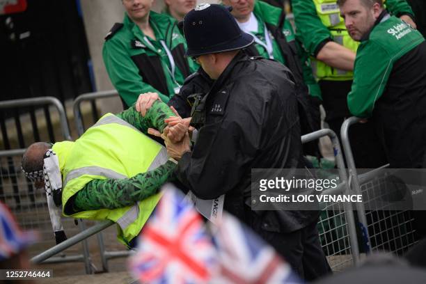 Police officers make an arrest close to the 'King's Procession', a journey of two kilometres from Buckingham Palace to Westminster Abbey in central...