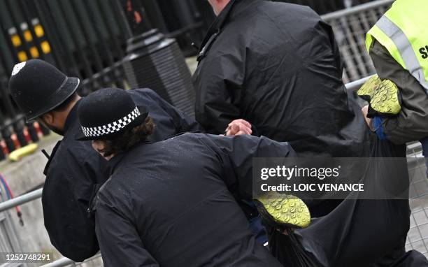 Police officers take away a protester close to the 'King's Procession', a journey of two kilometres from Buckingham Palace to Westminster Abbey in...