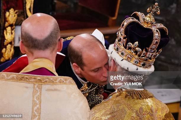 Britain's Prince William, Prince of Wales kisses his father, Britain's King Charles III, wearing St Edward's Crown, during the King's Coronation...