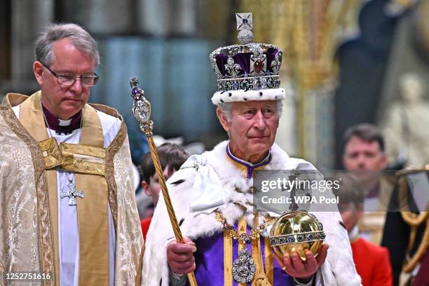Britain's King Charles III wearing the Imperial state Crown carrying the Sovereign's Orb and Sceptre leaves Westminster Abbey after the Coronation...