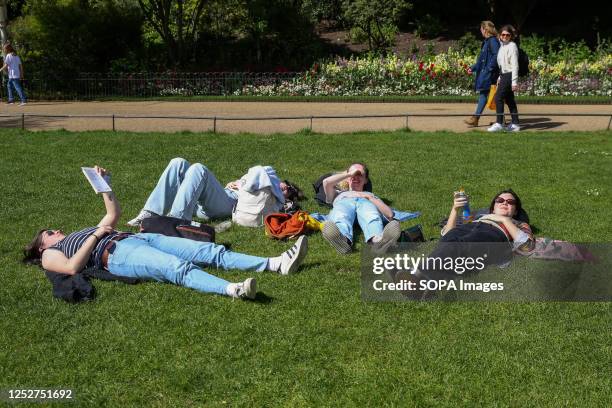 Friends enjoy the sunny weather in St James's Park in London on the eve of the coronation of King Charles III.