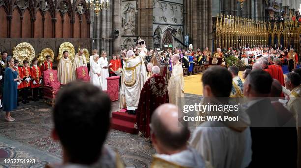 King Charles III is crowned with St Edward's Crown by The Archbishop of Canterbury the Most Reverend Justin Welby as Camilla, Queen Consort looks on...