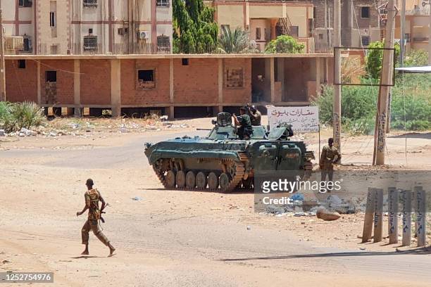 Sudanese Army sodliers walk near armoured vehicles stationed on a street in southern Khartoum, on May 6 amid ongoing fighting against the...