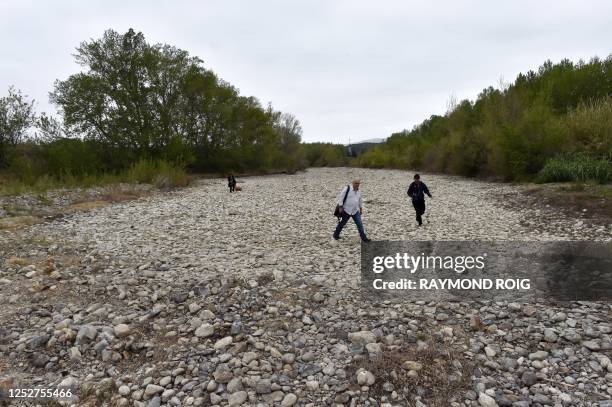 People cross the dried up river bed of the Agly coastal river during the French minister's for agriculture visit as southern France undergoes...